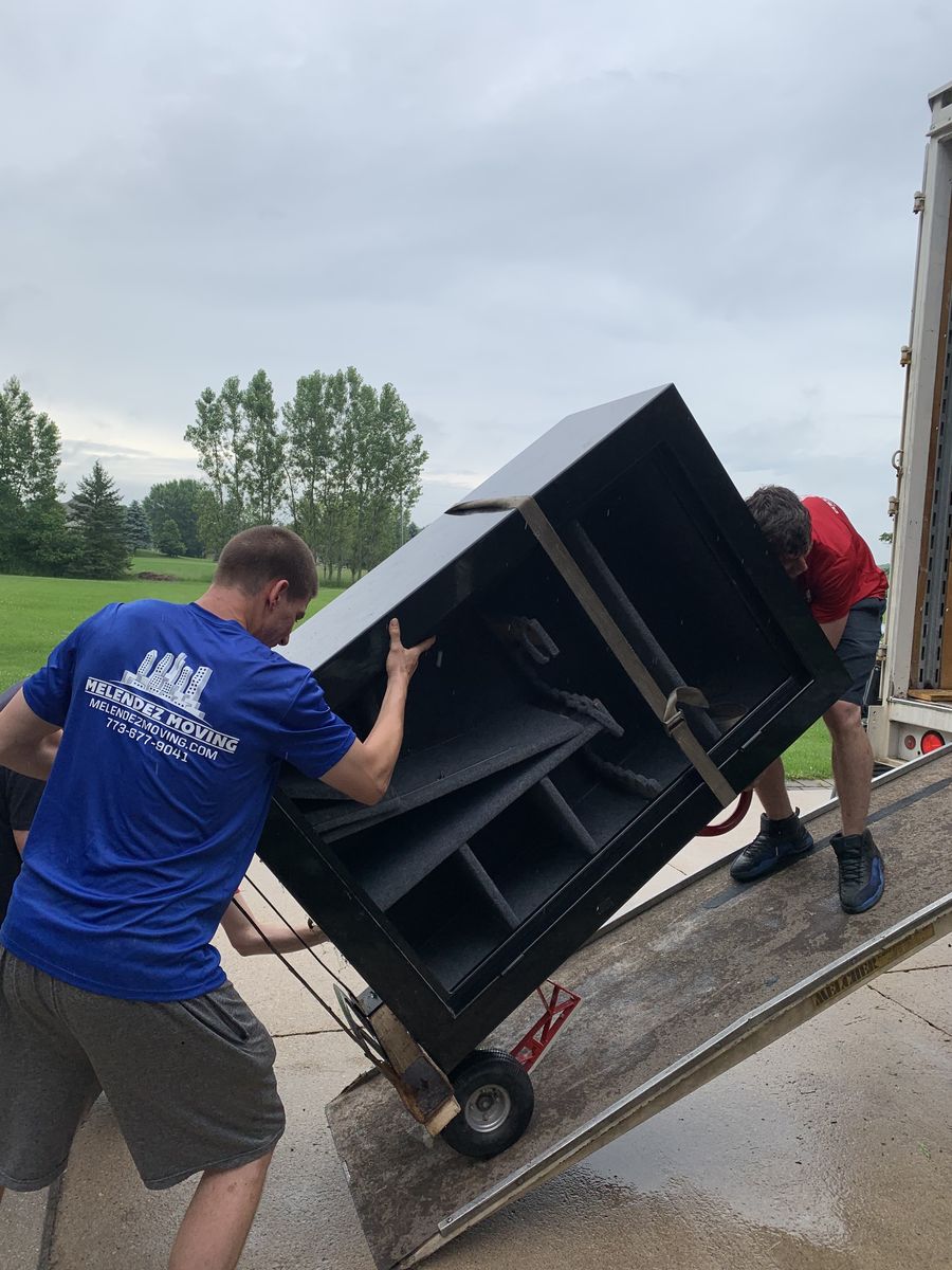 Melendez Moving crew loading a wrapped cabinet up a truck ramp